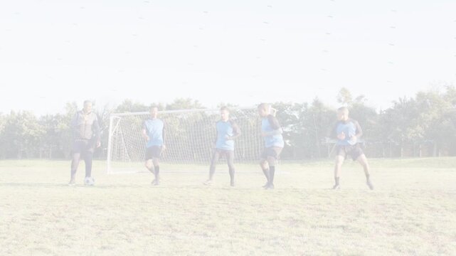 Soccer kicker planting and kicking ball, four in blue kit forming wall near goal, shifting blocking