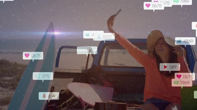 Woman raising phone on truck tailgate posing by surfboard and generating likes driving social reach