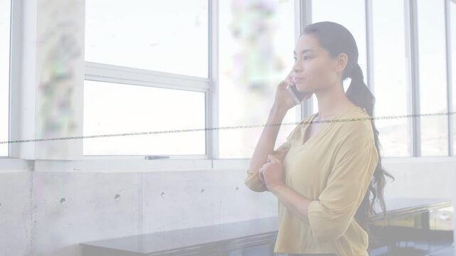 Office woman raising phone, taking business call by big windows with blurred plant and faint line