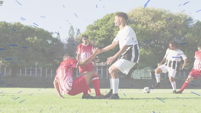 Soccer player helping red player after tackle on pitch, animated arrow showing ball resuming play