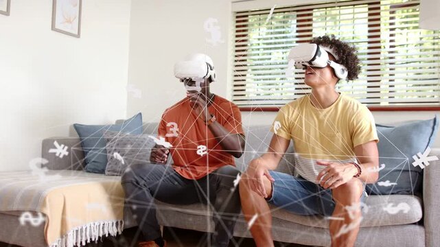 Two men on sofa, controller tap activating finance AR, selecting currency icons for market insight