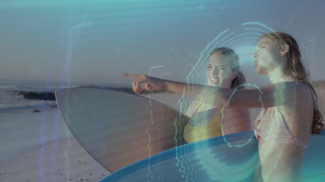 Two surfers holding surfboards on beach, one pointing, scouting waves while blue overlays sweeping