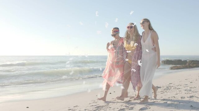3 women linked arms walking on beach for travel wind lifting wraps overlays fluttering across frame