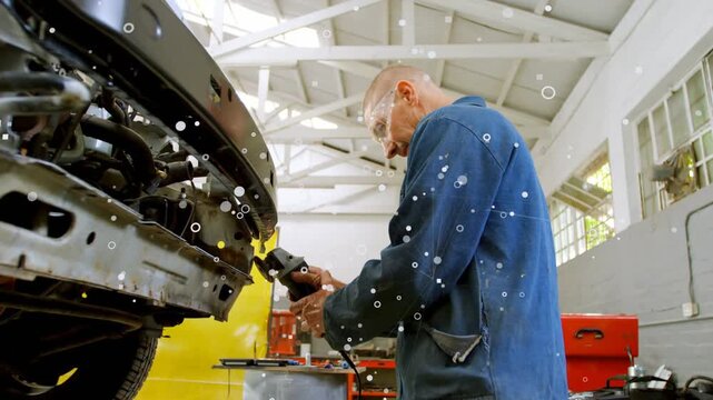 Mechanic starting grinder and grinding bumper for repair in automotive workshop, producing sparks