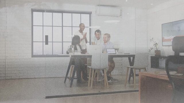 Four coworkers gathering around laptop, meeting slide appearing, pointing, celebrating decision
