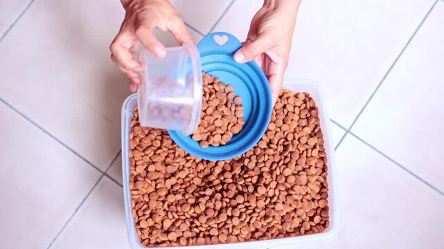 Person scooping dry kibble into a dog bowl