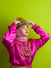 Naklejka premium Young Woman Wearing Traditional Pink Southeast Asian Costume And Hijab Adjusting Embroidered Headdress