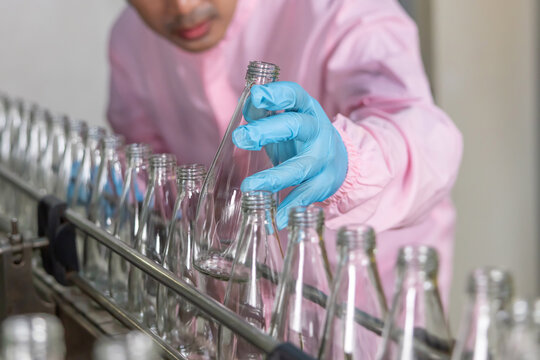 Worker hand picking up a bottle juice in a factory