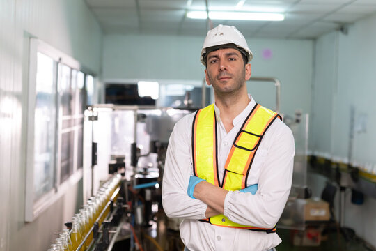 Worker in a production facility stands with arms crossed during a shift