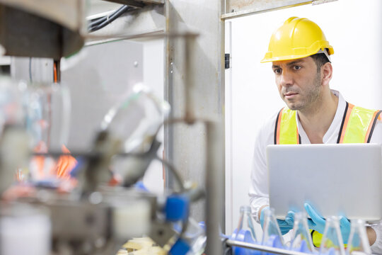 Worker checks on bottle production line in a factory