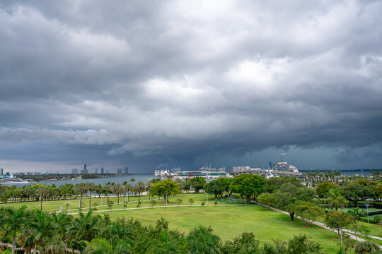 Wide panoramic view of Miami bay under stormy sky. Green park landscape overlooking Biscayne Bay and Port of Miami with heavy dark storm clouds above the horizon.