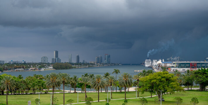 Impending storm over Biscayne Bay and Miami harbor. Heavy dark rain clouds moving over the tropical waters of Miami with port infrastructure and city in background.
