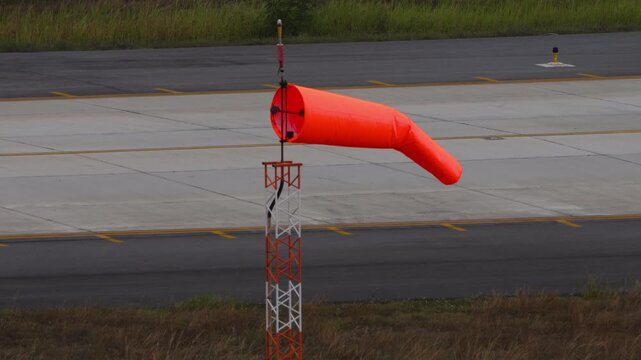 Windsock blow in wind to show speed and direction of wind gusts. Windsock with cloudy sky in the background. Conical tube in fabric used as a basic guide for the direction and speed of the wind.