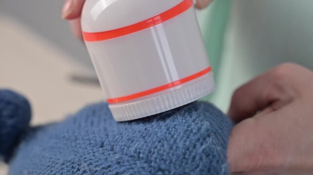 A woman revives the look of her knitted garments with a lint remover.