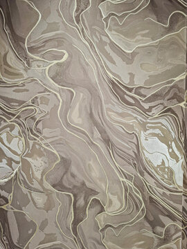 Fluid pattern background with golden and beige lines on textured fabric surface creating a marble effect