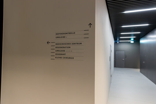 Moderne Wegweiser-Beschilderung in einem Krankenhausflur mit minimalistischem Design und indirekter Beleuchtung