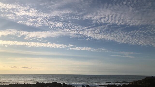 Scenic coastal view featuring altocumulus clouds over a peaceful horizon.
