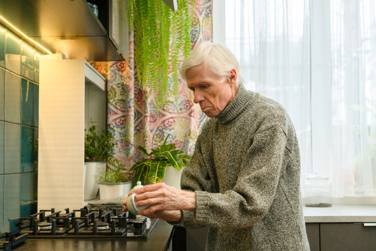An elderly man sets down various kitchen items onto the countertop. The action is part of daily routine, emphasizing independence and self-care. Grandfather organizing space.