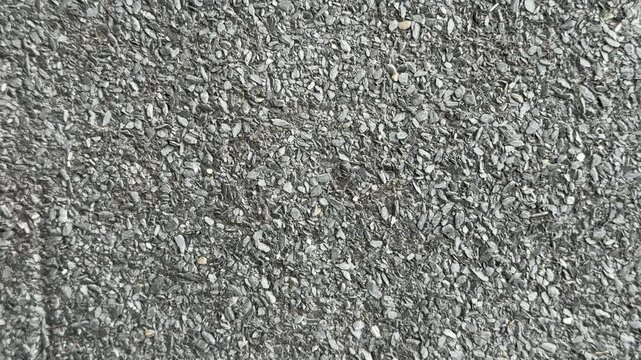 Close-up roof granules Uniflex waterproofing showing dense mineral granules embedded in dark asphalt membrane, high detail macro
