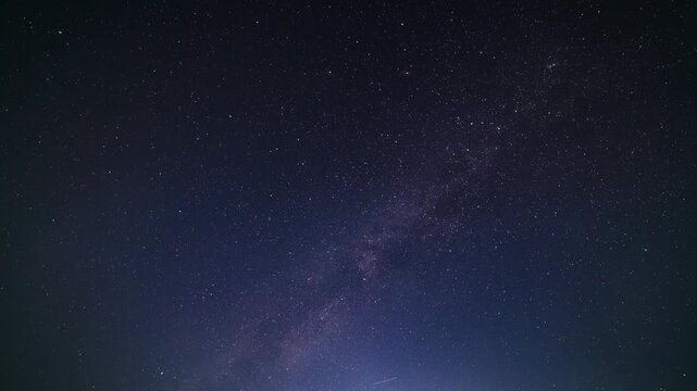 Ultra-wide angle starry night milky way galaxy time lapse with satellite streaks across the frame. Upward direction, full-frame horizonless view.