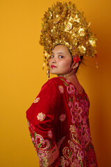 Naklejka premium Young Indonesian Asian Woman Wearing Golden Headdress And Embroidered Red Traditional Costume Portrait