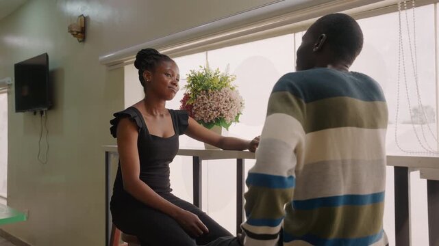 Intimate cafe conversation between couple near window offering hand, soft natural light, bouquet on table, casual sweater, warm smiles and shy laughter, cinematic close framing conveying budding