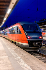 Fototapeta premium Passenger train at the station at night. View of the front part of transport on the tracks.