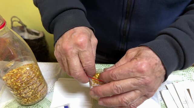 Close-up white male salesman packing bee pollen into transparent bag, hands pressing and sealing pouch on table with yellow