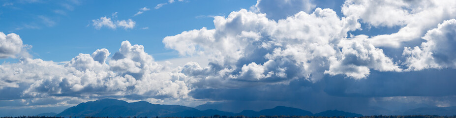 Fototapeta premium Dramatic Cloudscape Over Mountains and Horizon in British Columbia, Canada Under Blue Sky