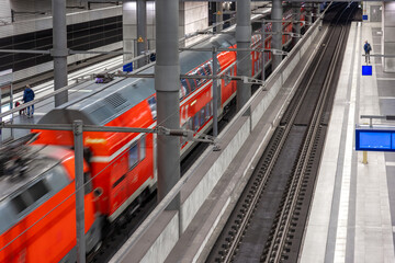 Naklejka premium Red passenger train arriving at modern railway station. Railway traffic and public infrastructure.