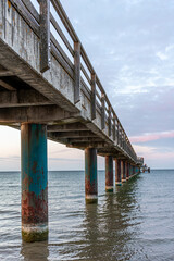 Fototapeta premium Vertical perspective under a sea bridge. Old columns in water during sunset.