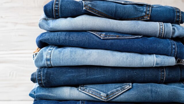 Neatly stacked various blue jeans showing texture and shades fashion background
