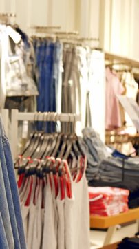 Denim jackets hanging on store rack, merchandiser arranging rows under warm lighting, casual boutique vibe with folded jeans, hangers and sale tags, textured cotton and vintage wash details