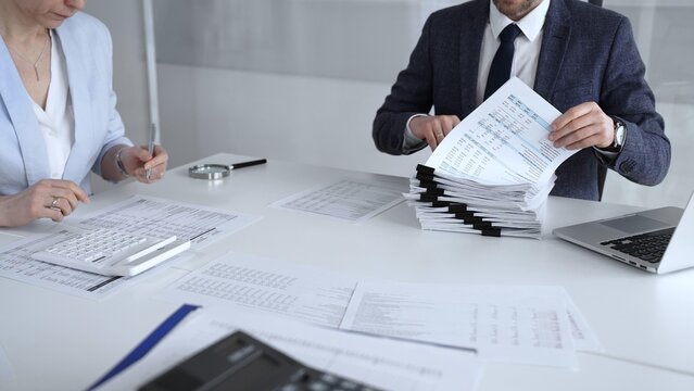 Professional accountant team analyzing corporate financial data, managing paperwork, and preparing tax reports, collaborating on bookkeeping and auditing tasks at a desk. Audit and taxes
