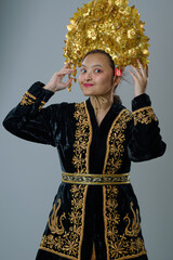 Naklejka premium Young Indonesian Asian Woman Wearing Traditional Embroidered Black Robe and Ornate Gold Headdress Cultural Portrait