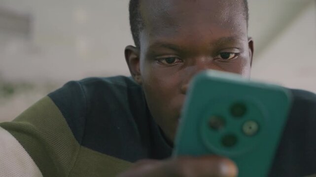 Black man reading reply on phone, subtle smile and softened shoulders, warm indoor lights and film grain, intimate closeup conveying relief, connection and tender optimism after message
