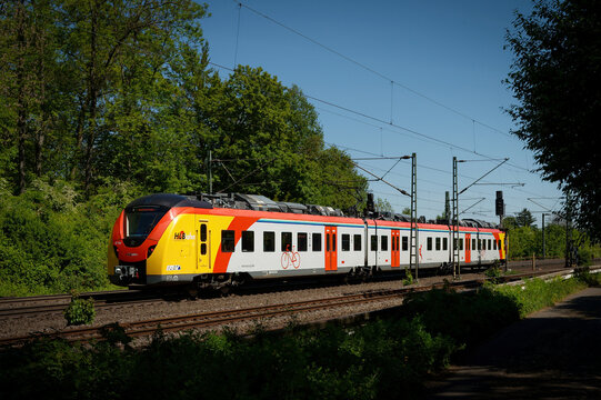 Cologne, Germany April 29 2026: A modern HLB regional train passes through a green landscape on a sunny day near cologne