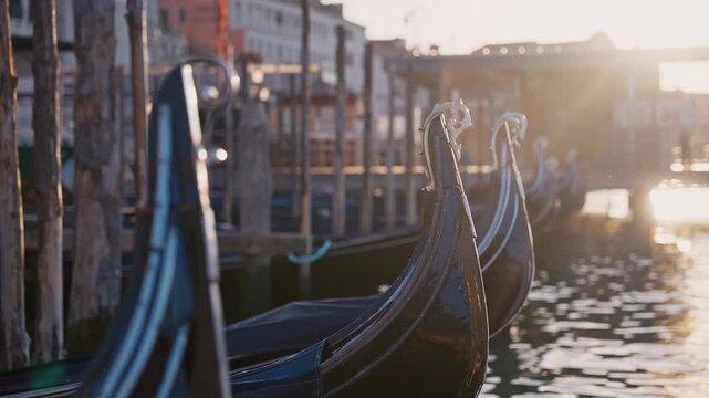 Venetian gondolas with ferro ornament moored, floating on calm morning water