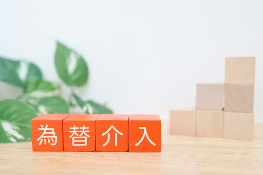 為替介入。円高進行を示す右肩上がりの階段状の積み木。赤いブロック文字