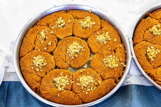 Turkish traditional dessert in various flavors. Pieces of turkish traditional declious dessert pohlava with nuts and honey. Turkish sweets. Turkish Burma Kadayif with Pistachio Powder in Tray Dessert 