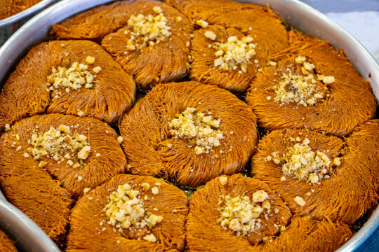 Turkish traditional dessert in various flavors. Pieces of turkish traditional declious dessert pohlava with nuts and honey. Turkish sweets. Turkish Burma Kadayif with Pistachio Powder in Tray Dessert 