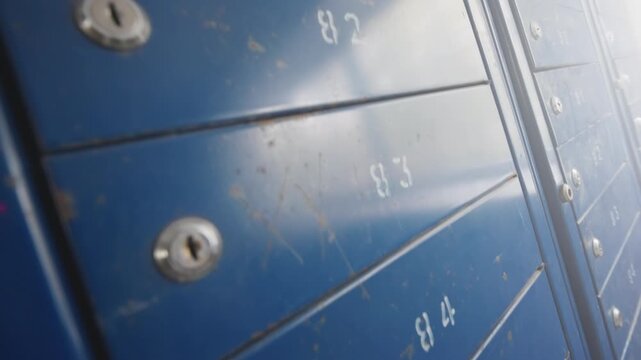 Rows of Blue Metal Mailboxes with Numbers and Locks in Apartment Building | Dutch Angle Ultra-Wide Close-Up View | Urban Residential Postal Infrastructure