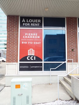 Gatineau, Quebec, Canada &ndash; March 10, 2026: A storefront window features "For Rent" signs for Pierre Charron, a commercial real estate broker, displayed on a brick building on rue Laval.