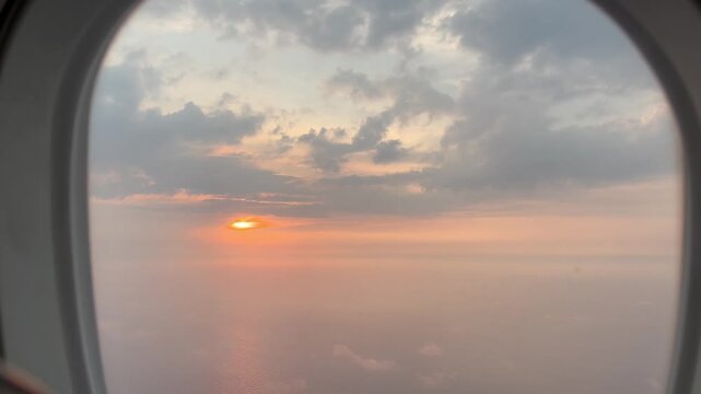 Cinematic sunset view from airplane window flying above clouds