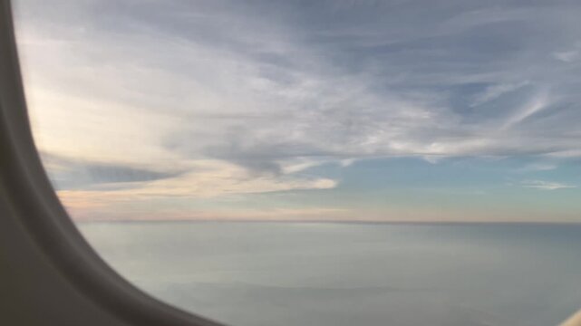 Airplane window view of clouds and sky at cruising altitude