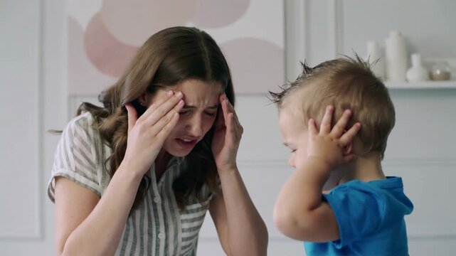 Young woman wearing striped shirt interacting with toddler boy in blue t-shirt, medium shot