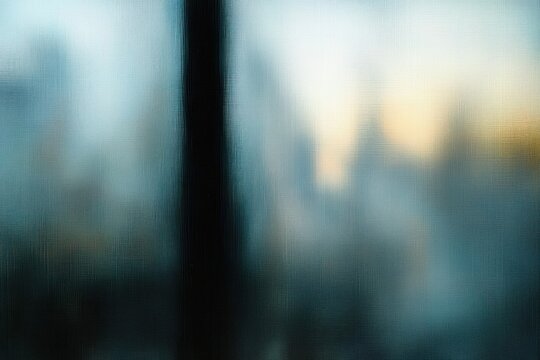 blurred city skyline seen through textured window glass with a dark vertical frame and calm sunrise glow