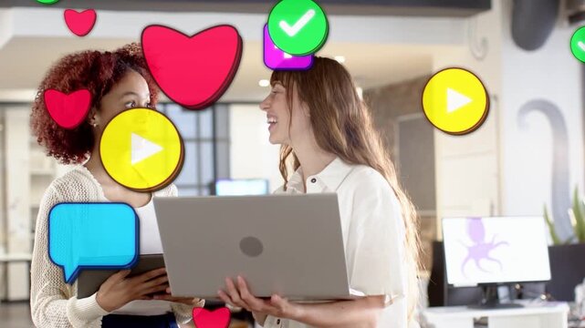 Coworkers viewing laptop, tablet after laughing as hearts rising over frame, showing social buzz