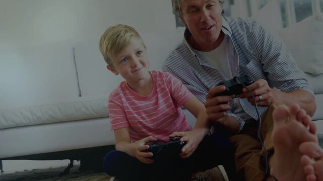 Dad and son pressing wired controllers, gaming and bonding, camera rising showing smiling faces