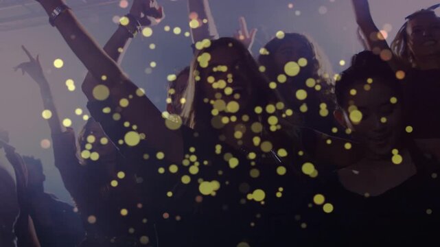 Yellow bokeh overlay appearing covering frame, three women stepping raising arms, celebrating music